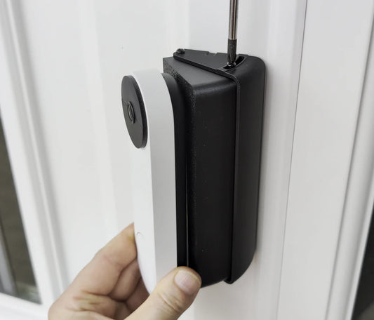 Google Nest doorbell being fitted onto the adjustable wedge mount on a white door frame, with a screwdriver tightening the top screw
