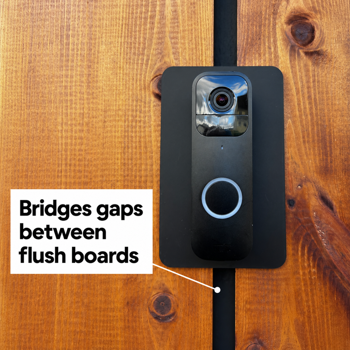 Black wall plate bridging the gap between two flush timber boards behind a Blink doorbell